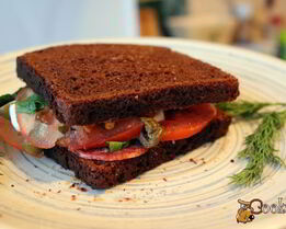 Сендвич из ржаного хлеба с салями и помидором